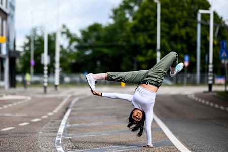 Logistx balances on one hand and grabs her leg with the other hand