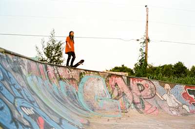 Alyssa Lee steht auf einer vollgesprühten Betonrampe, ihr Tail ist auf dem Coping eingeloggt. Sie macht sich bereit für einen Drop-In