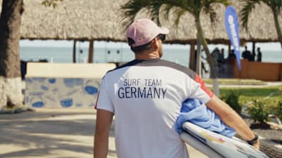 Surfprofi Leon Glatzer trägt seine Boards für Team Germany zum Strand um dort einen Wettkampf zu surfen.