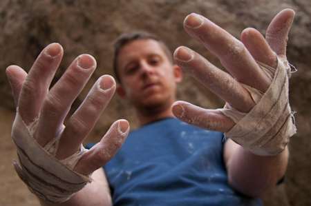 Tommy Caldwell shows his wrapped hands to the camera.