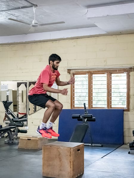 Srikanth Kidambi performs box jumps while working out in a gym.