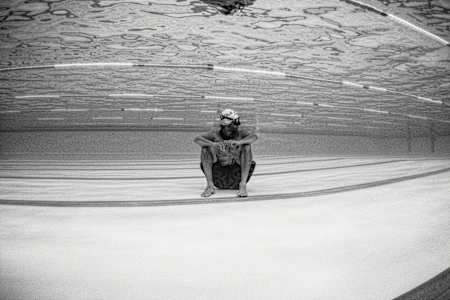 Nadador sentado en el fondo de una piscina.