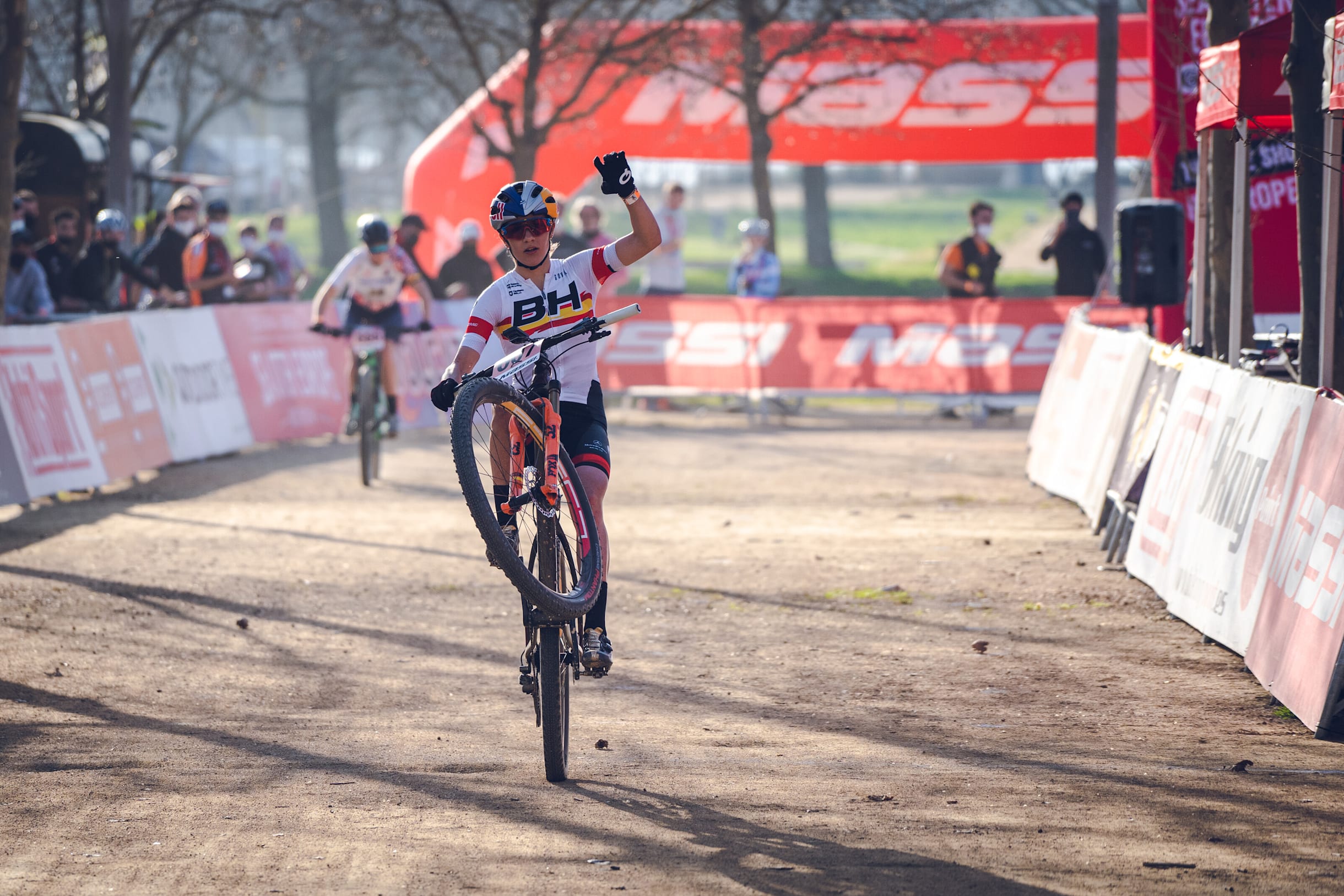 Rocío del Alba haciendo el caballito con su bici de MTB y levantando el puño para entrar a meta en una prueba UCI de Banyoles (Girona).