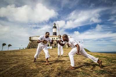 Homens jogando capoeira no Farol da Barra, em Salvador