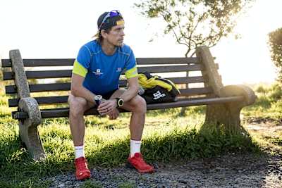 El corredor Ryan Sandes descansa en un banco después de un entrenamiento.