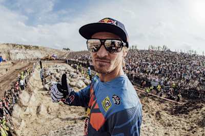 Tadeusz Błażusiak pozuje do zdjęcia na mecie Red Bull 111 Megawatt. W tle tłum fanów enduro