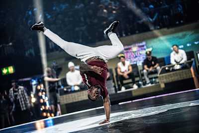 B-Boy Kid Colombia standing on one hand during a performance at the red Bull BC One World Final 2018.