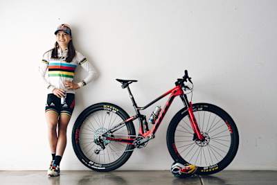Kate Courtney poses for a photo alongside her bike.