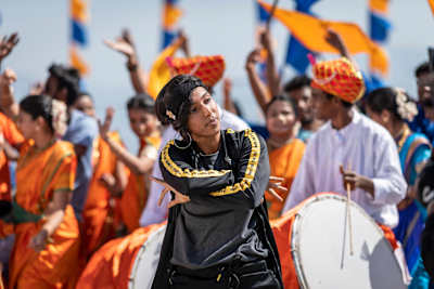 La B-Girl Jo hace una pose delante de un grupo de músicos y gente.