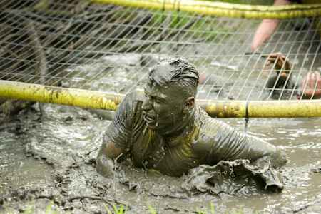 Participant crawls underneath a net at the Dirty Double event in the UK.