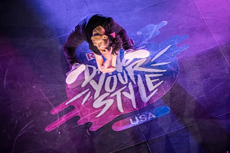 Skitzo is posing on his knees with the back arched and doing a flexible gesture with the hands.