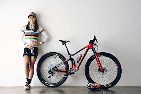 Kate Courtney poses for a photo alongside her bike.