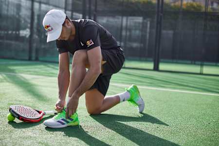 Ale Galán schnürt seine Schuhe vor dem Padel-Match.
