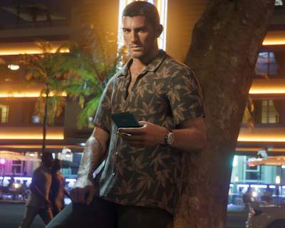 Jason Duval leans against a tree and scrolls on his phone in a scene from GTA 6.