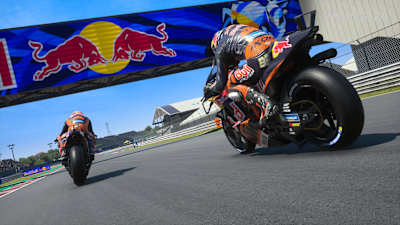 Captura de pantalla de MotoGP 24 muestra a Jack Miller y Brad Binder bajo una pancarta de Red Bull en Misano.