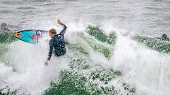 Jamie O'Brien carries his board while surfing in San Francisco while filming for No Contest S2 E1
