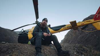 Brage Vestavik sits beside a yellow Red Bull helicopter in the Chilean mountains.