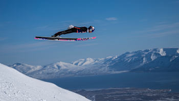Red Bull athlete Ryōyū Kobayashi of Japan soars high during an adrenaline-packed ski jump above Akureyri, Iceland, set against majestic snowy peaks in April 2024