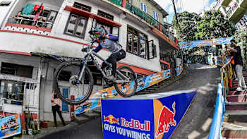 A participant launches off a ramp at Red Bull Tlang Ruam in Aizawl, India, on November 8, 2025, showcasing gravity-defying downhill biking energy in an urban setting