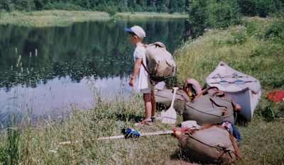 Young Benny Marr stood by canoe and camping kit.