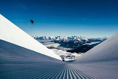Un skieur freestyle s’envole dans un immense half-pipe.