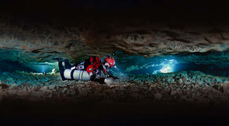 Cave diver Jill Heinerth pictured squeezing through a claustrophobia tunnel deep under surface.