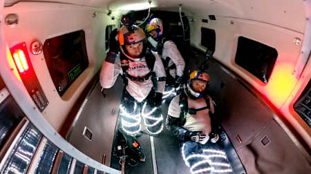 Skydivers from Red Bull Air Force preparing to jump with LED lights wrapped around their legs.