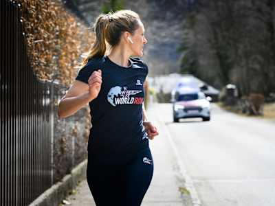 Wings for Life World Run Teilnehmerin trainiert mit der Wings for Life World Run App und wird dabei vom Catcher Car jagt.