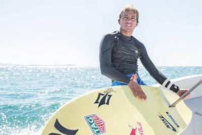 Kai Lenny auf einem Boot mit seinem Hydrofoil-Surfboard.