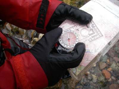 Person holds compass over an OS map.
