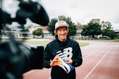 El triatleta Sebastian Kienle delante de una cámara de vídeo con su zapatilla New Balance con placa de carbono.