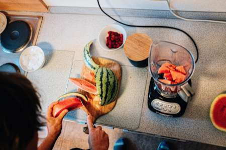 Triathlet Sebastian Kienle schneidet bei der Zubereitung eines Protein-Shakes eine Wassermelone.
