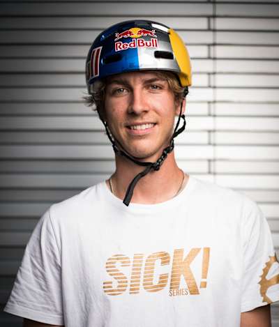 Fabio Wibmer posiert in SICK! Shirt mit Red Bull Helm für die Kamera.