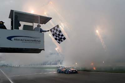 La imagen muestra la bandera a cuadros en el final de temporada en el Hockenheimring de la temporada 2013 del DTM con el ganador Matthias Ekström.