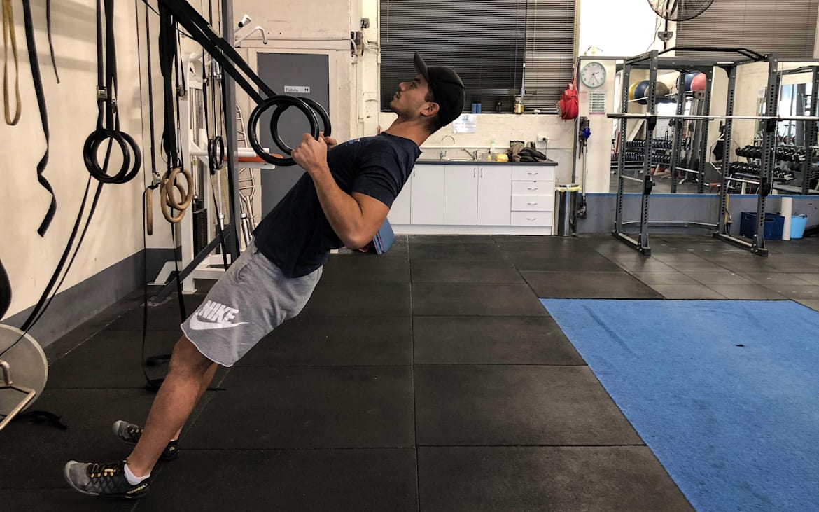 Un atleta tira de unos aros montados en la pared.