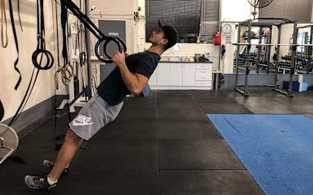 Un atleta tira de unos aros montados en la pared.