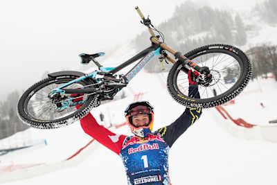 Mountain biker Max Stöckl holds his bike aloft in celebration after racing down the Streif in Austria.