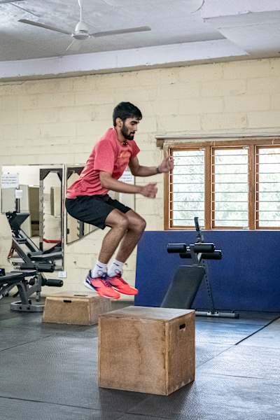 Srikanth Kidambi performs box jumps while working out in a gym.