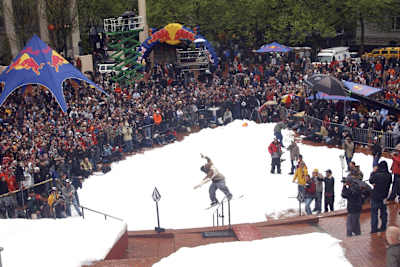 A snowboarder jibs a handrail in front of a packed crowd at Red Bull Heavy Metal in Portland, Oregon.
