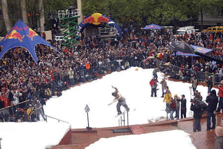 A snowboarder jibs a handrail in front of a packed crowd at Red Bull Heavy Metal in Portland, Oregon.