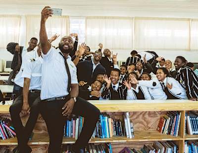 An instructor from the iFly Academy, South Africa's first black-owned aviation school, takes a selfie with school students during a visit.