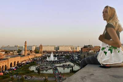 Cassie De Pecol sitting on a building rooftop looking at the view in Iraq.