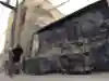 A man jogs past a highly-decorated alleyway with graffiti and wheelie bins.