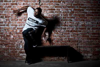 Famed popping dancer Popin' Pete posing in front of a brick wall.