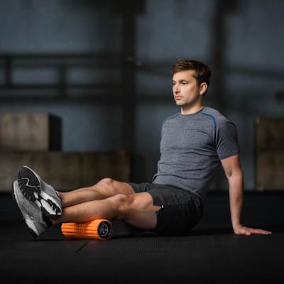 A man uses a foam roller on his calves.