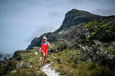 Running down a singletrack trail with mountain in background.