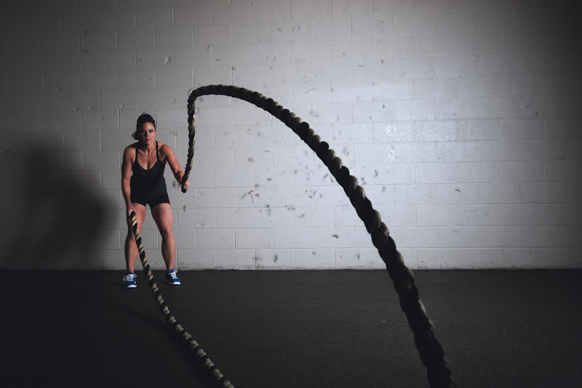 Una mujer usa “battle ropes” en un gimnasio.