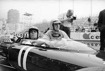 American actor James Garner in a racing car at the Monaco Grand Prix. Kneeling beside him is Ferrari driver Lorenzo Bandini