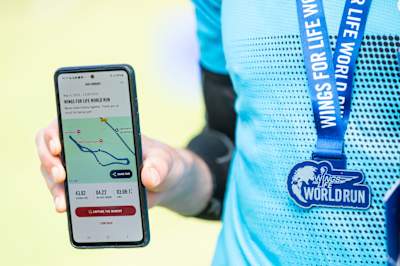 Un coureur de la Wings for Life World Run 2025 montre ses résultats dans l'appli à Sarajevo, capturant l'énergie de l'événement Red Bull et son appui pour la recherche sur la moelle épinière.