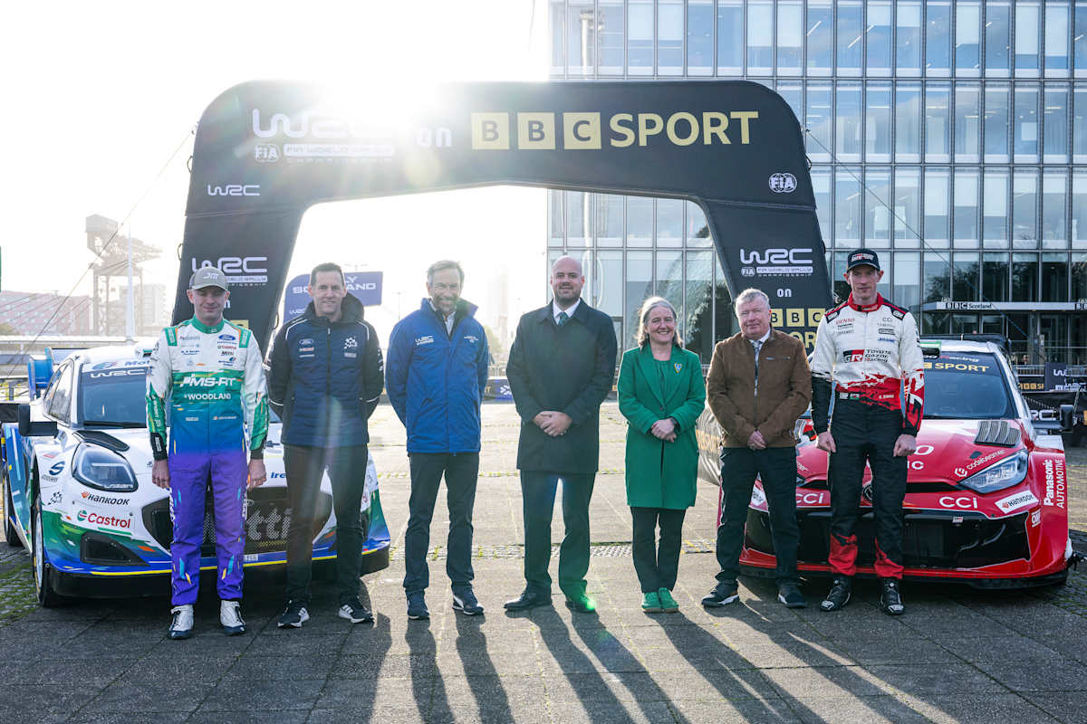 WRC drivers and officials stand beneath a "WRC on BBC Sport" arch alongside two Rally1 cars at the deal's launch event.
